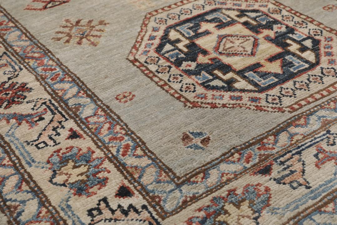 Alfombra pasillo de Oriente Medio anudada a mano con medallones geométricos en tonos grises, azules y rojos.