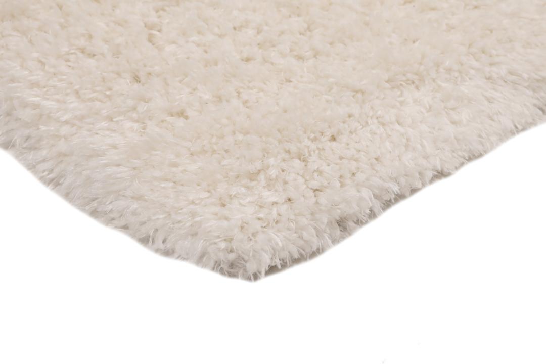 Um tapete bege claro felpudo com uma textura de pelo suave e profundo.