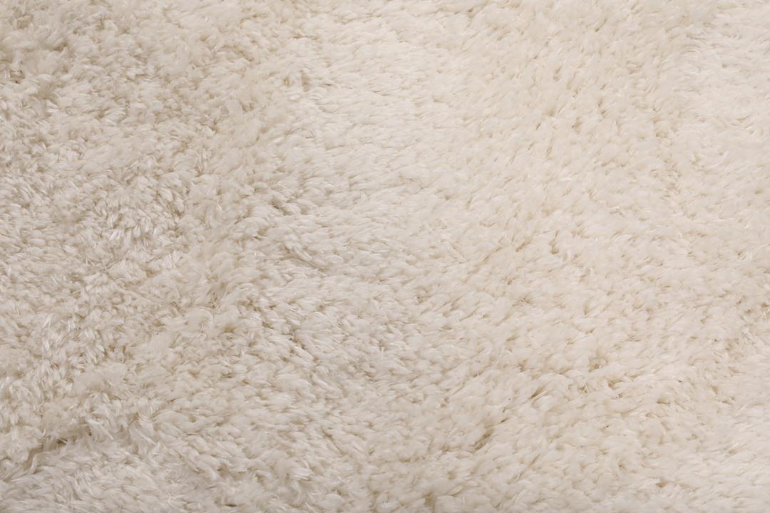 Um tapete bege claro felpudo com uma textura de pelo suave e profundo.