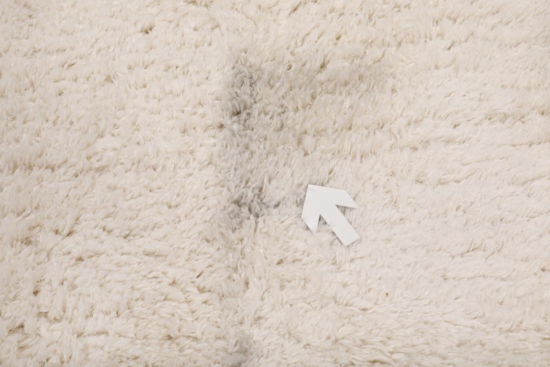 Um tapete bege claro felpudo com uma textura de pelo suave e profundo.