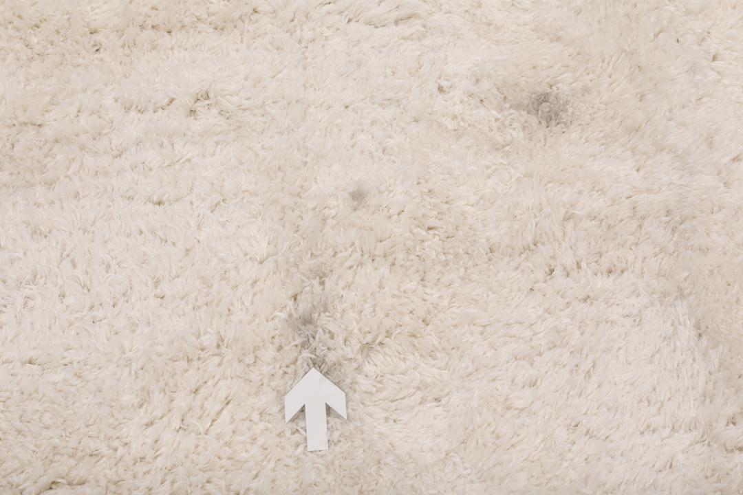Um tapete bege claro felpudo com uma textura de pelo suave e profundo.