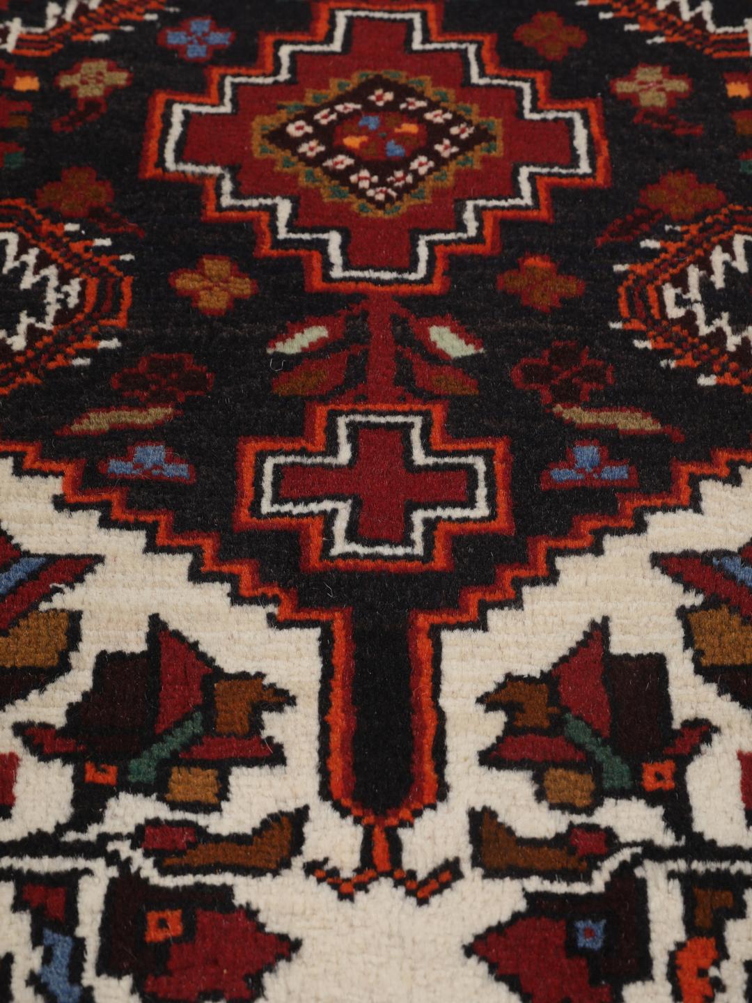 Handgeknoopt Beluch-tapijt met geometrische motieven in donkerrode en zwarte tinten.