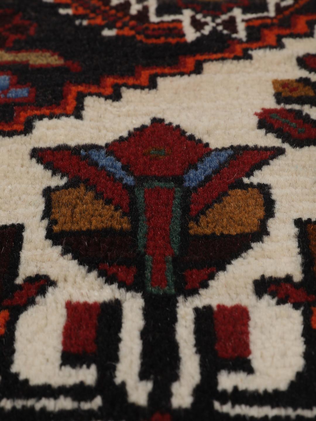Handgeknoopt Beluch-tapijt met geometrische motieven in donkerrode en zwarte tinten.