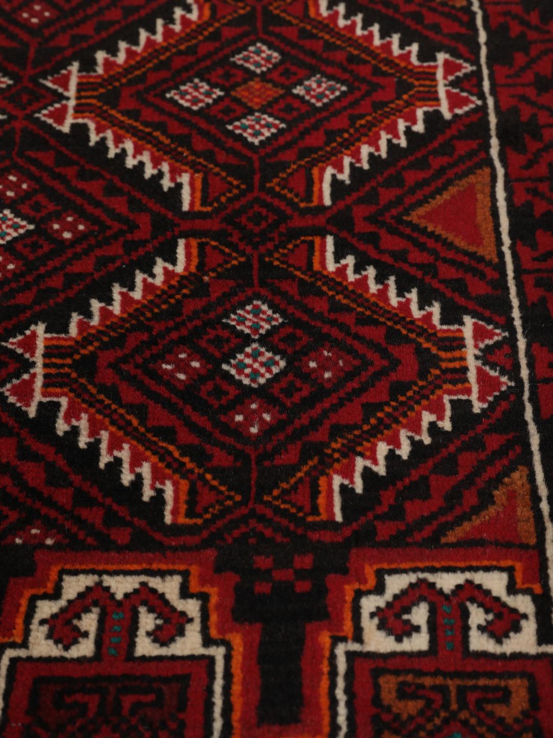 Handgeknoopt Beluch wollen tapijt uit het Midden-Oosten met een donkerrood geometrisch patroon.