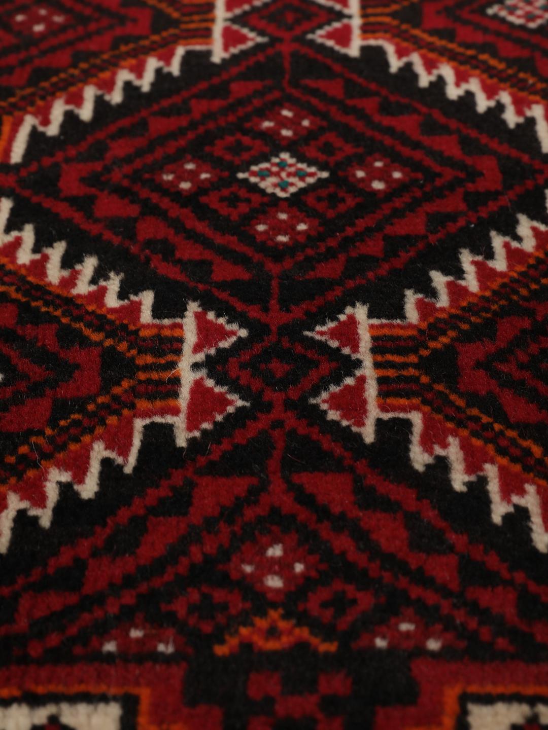 Handgeknoopt Beluch wollen tapijt uit het Midden-Oosten met een donkerrood geometrisch patroon.