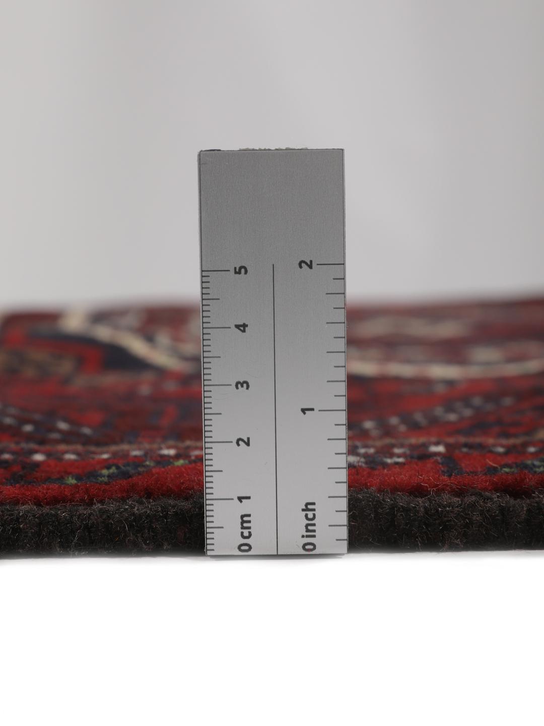 Et håndknyttet Beluch-tæppe fra Mellemøsten i dybe mørkerøde toner med geometriske motiver.