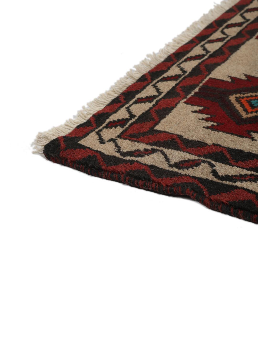 Een handgeknoopt Baluch tapijt uit het Midden-Oosten met een geometrisch patroon in rood en beige.