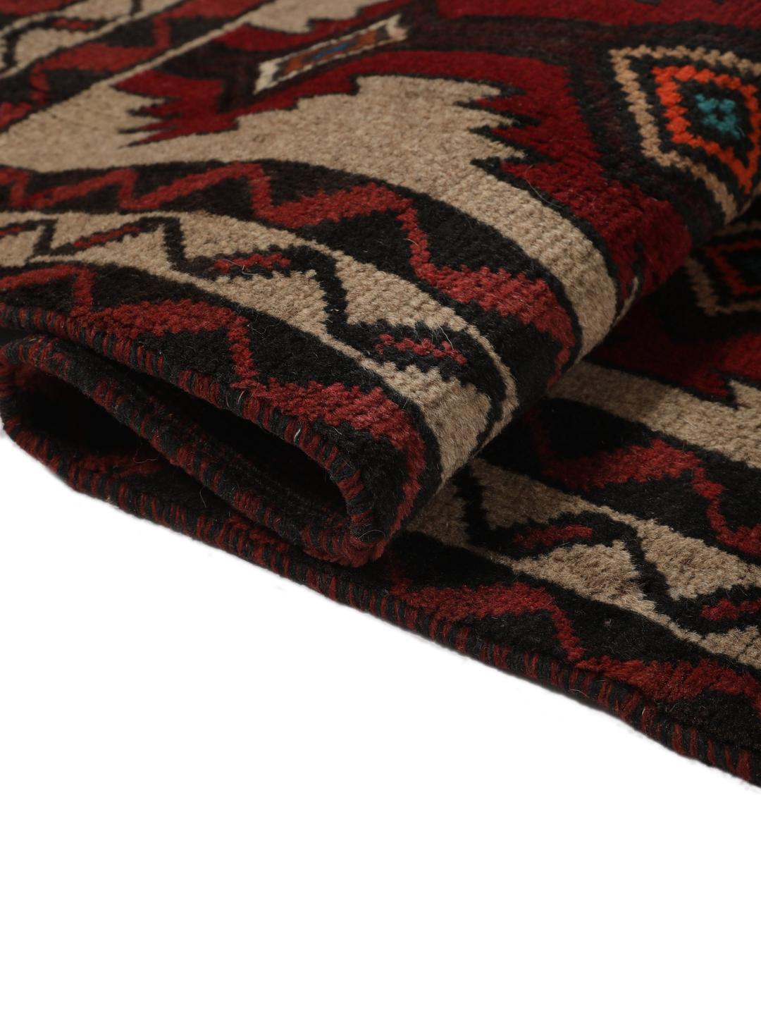 Een handgeknoopt Baluch tapijt uit het Midden-Oosten met een geometrisch patroon in rood en beige.