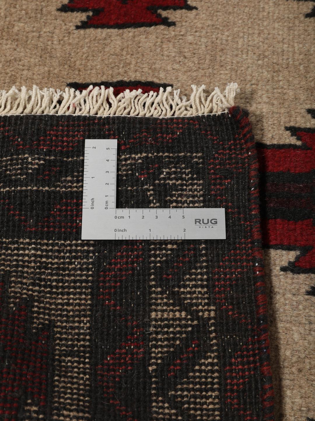 Een handgeknoopt Baluch tapijt uit het Midden-Oosten met een geometrisch patroon in rood en beige.