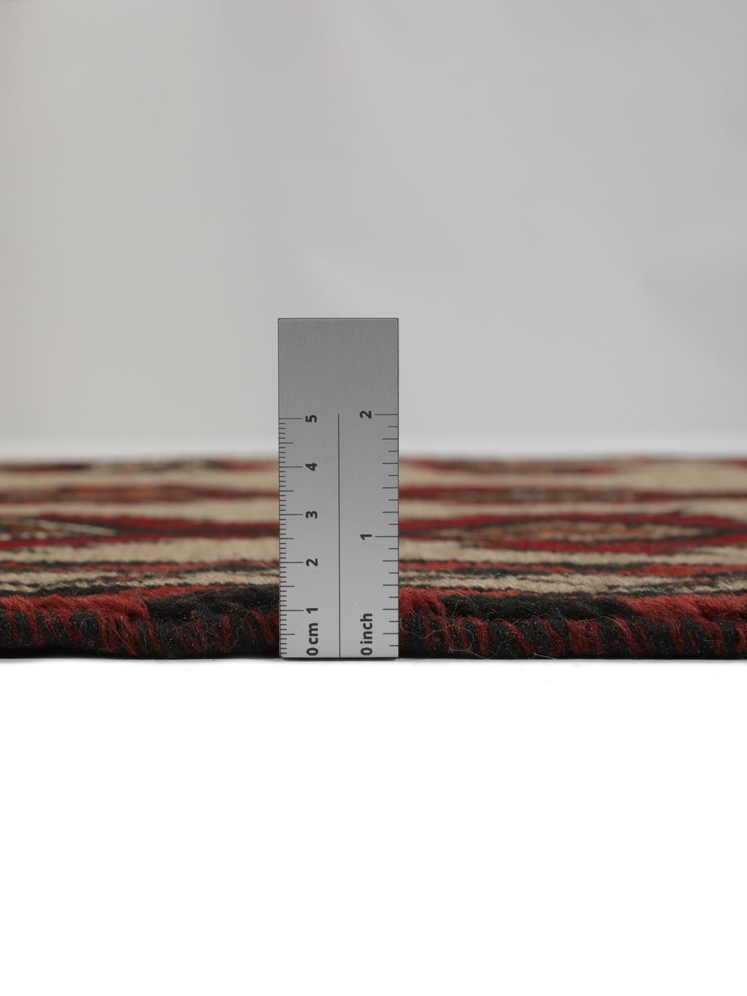 Een handgeknoopt Baluch tapijt uit het Midden-Oosten met een geometrisch patroon in rood en beige.