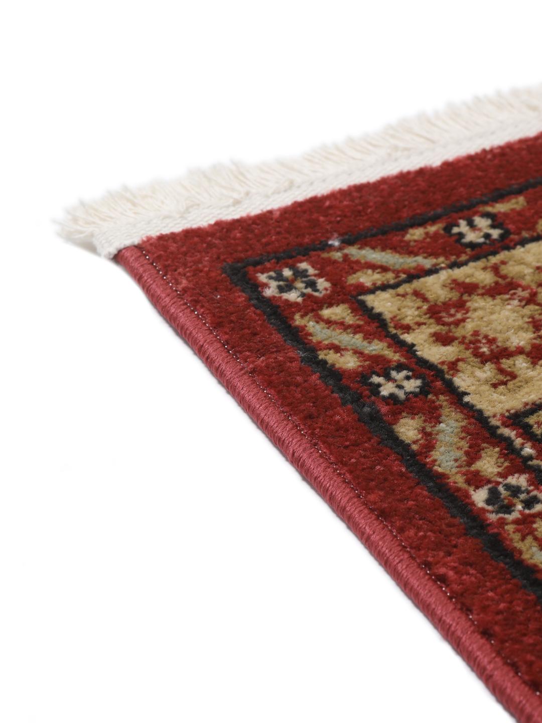 Et rødt og beige tæppe med et traditionelt mønstret design.
