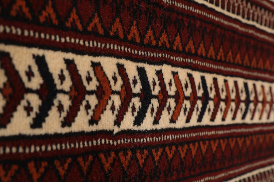 Et håndknyttet Turkaman-tæppe fra Mellemøsten i dyb rød med geometriske motiver.