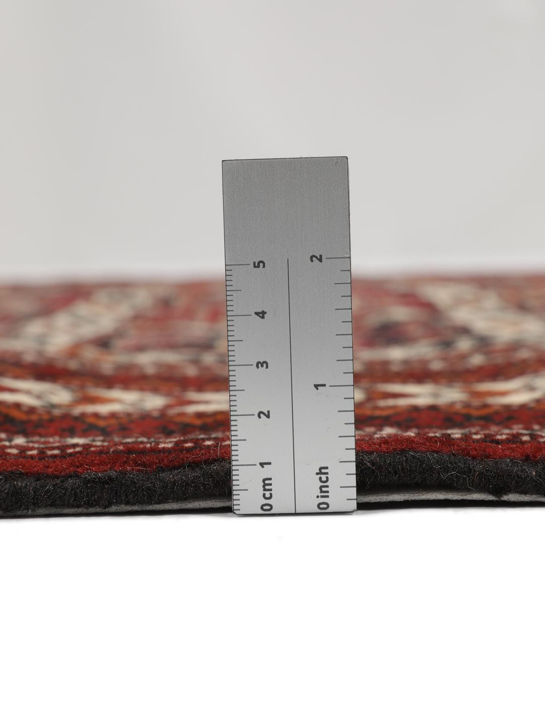 Et håndknyttet Turkaman-tæppe fra Mellemøsten i dyb rød med geometriske motiver.