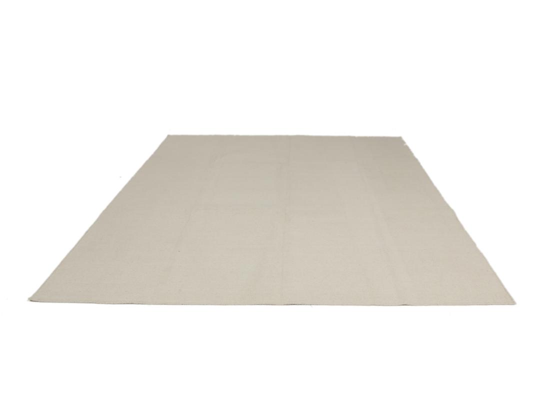 Um tapete Kilim tecido à mão, minimalista e de cor bege sólida, proveniente da Índia