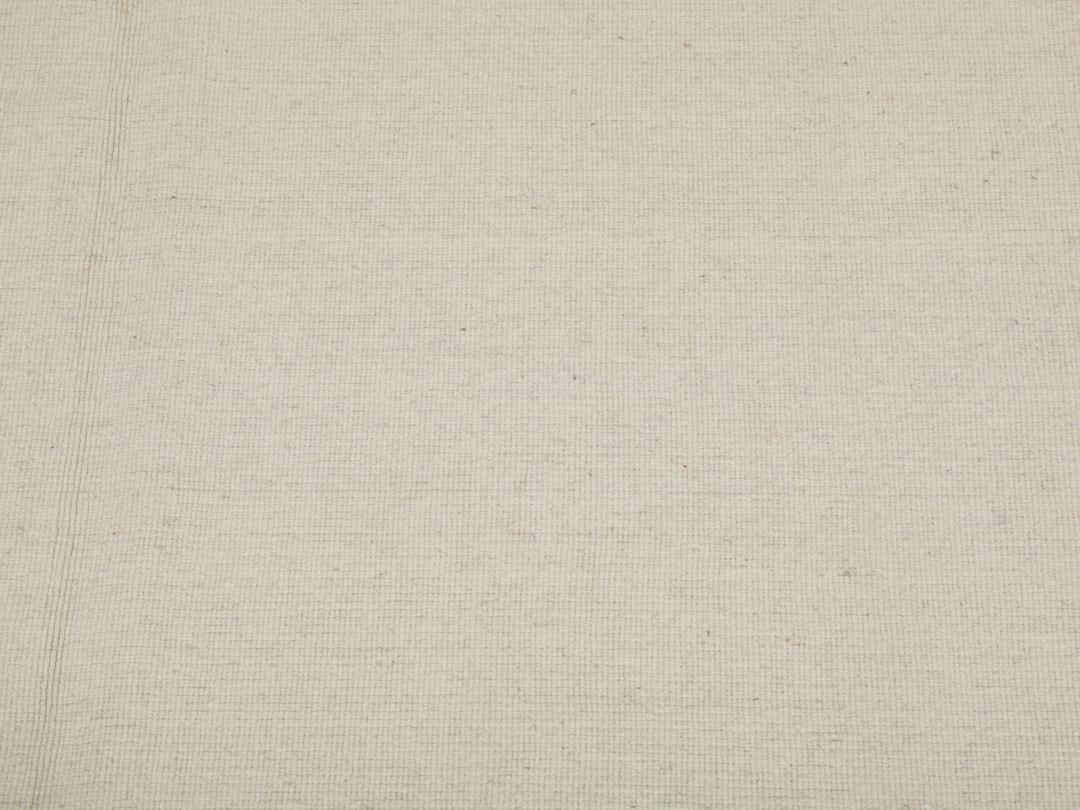 Um tapete Kilim tecido à mão, minimalista e de cor bege sólida, proveniente da Índia