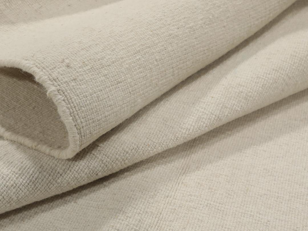 Um tapete Kilim tecido à mão, minimalista e de cor bege sólida, proveniente da Índia