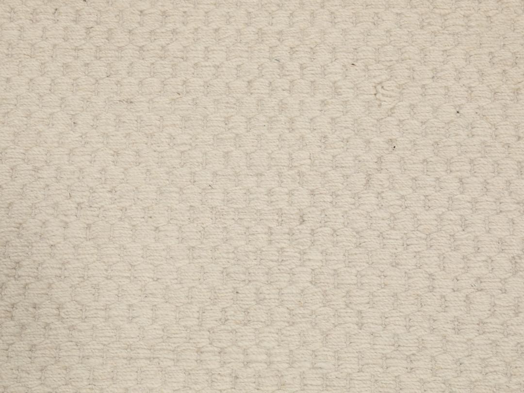 En minimalistisk, beige handvävd matta från Indien med en ren, texturerad yta.