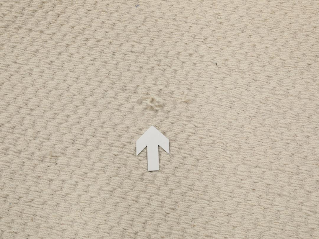 En minimalistisk, beige handvävd matta från Indien med en ren, texturerad yta.