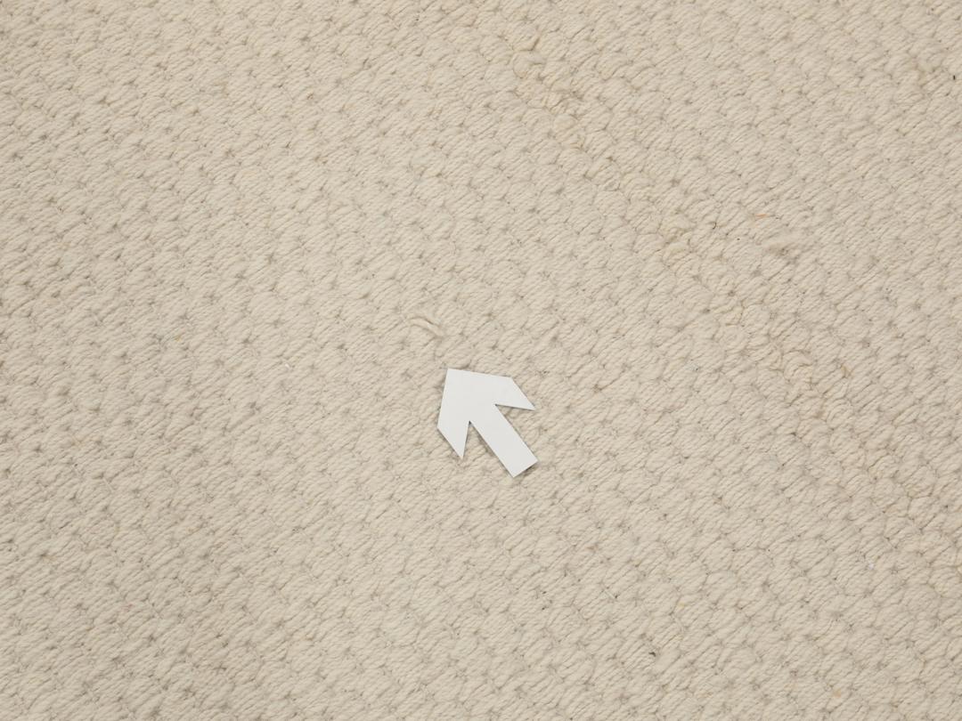 En minimalistisk, beige handvävd matta från Indien med en ren, texturerad yta.