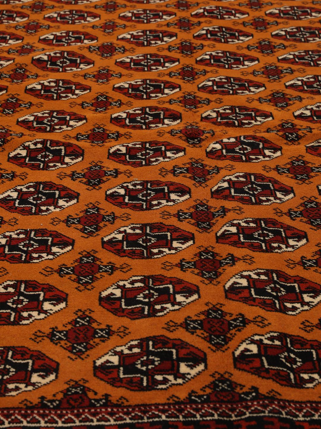 Hand-knotted Turkaman rug from the Middle East featuring an amber field and dark red border.