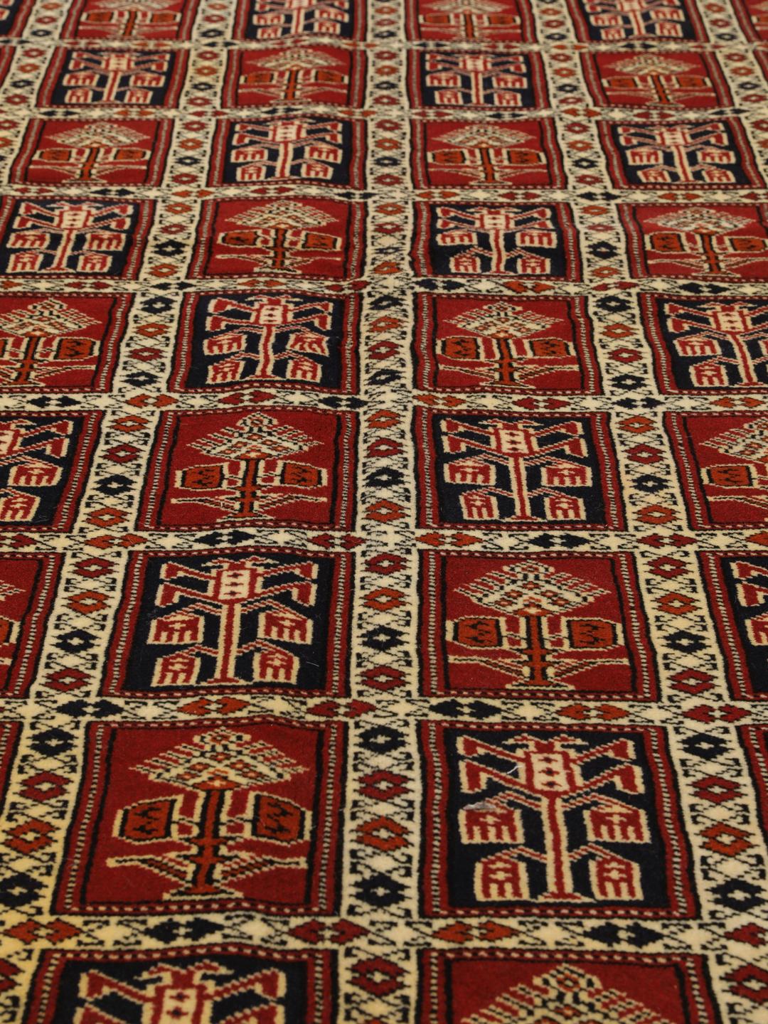 Een handgeknoopt Turkaman-tapijt uit het Midden-Oosten in dieprood met geometrische patronen.