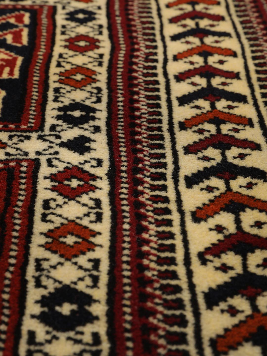 Een handgeknoopt Turkaman-tapijt uit het Midden-Oosten in dieprood met geometrische patronen.