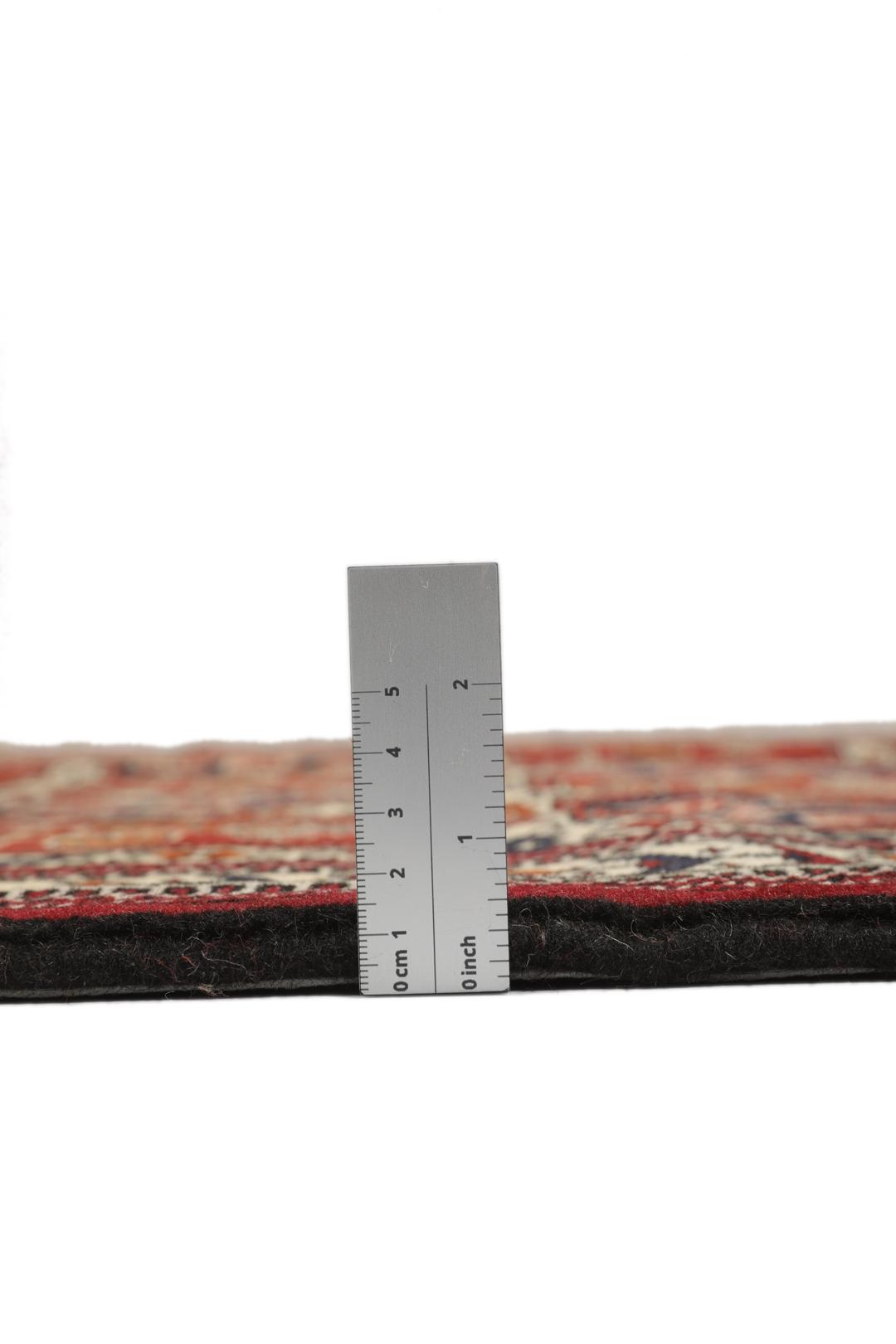 Een handgeknoopt Turkaman-tapijt uit het Midden-Oosten in dieprood met geometrische patronen.