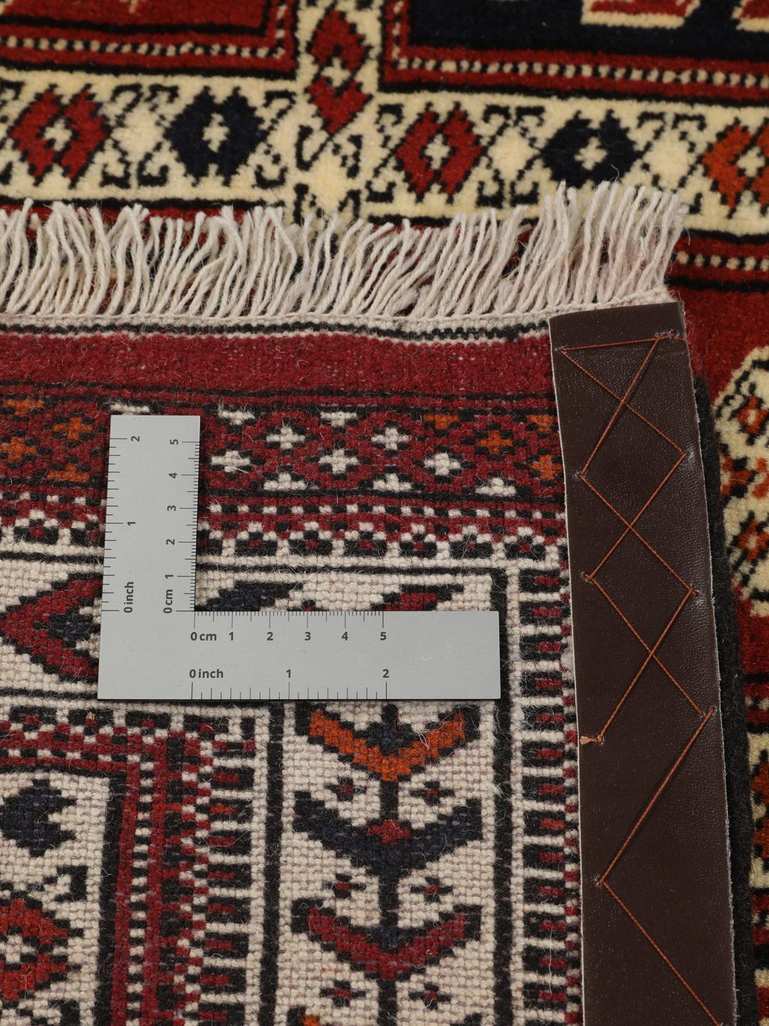 Een handgeknoopt Turkaman-tapijt uit het Midden-Oosten in dieprood met geometrische patronen.