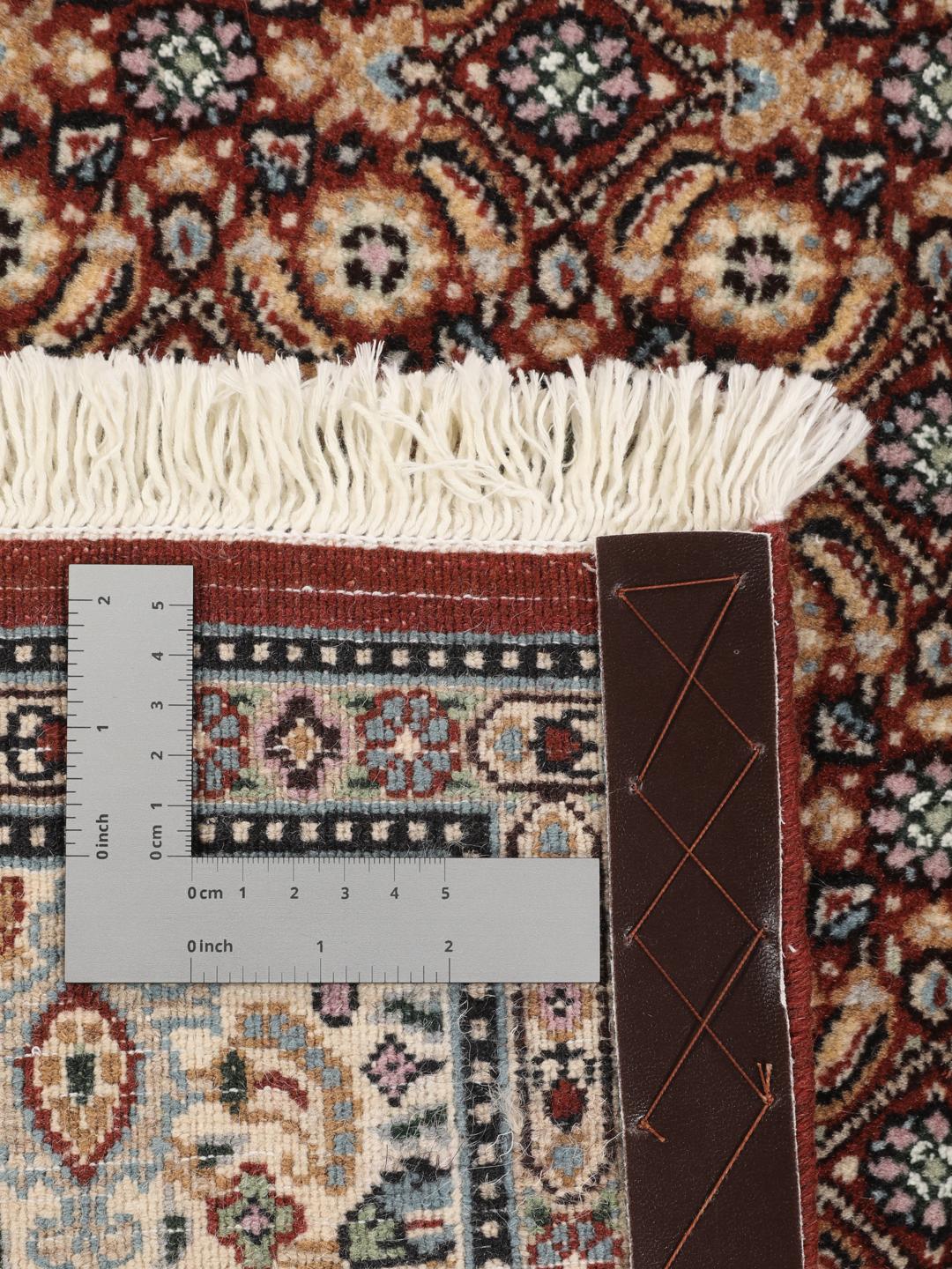 A hand-knotted Moud rug with traditional floral motifs in dark-red and blue tones.