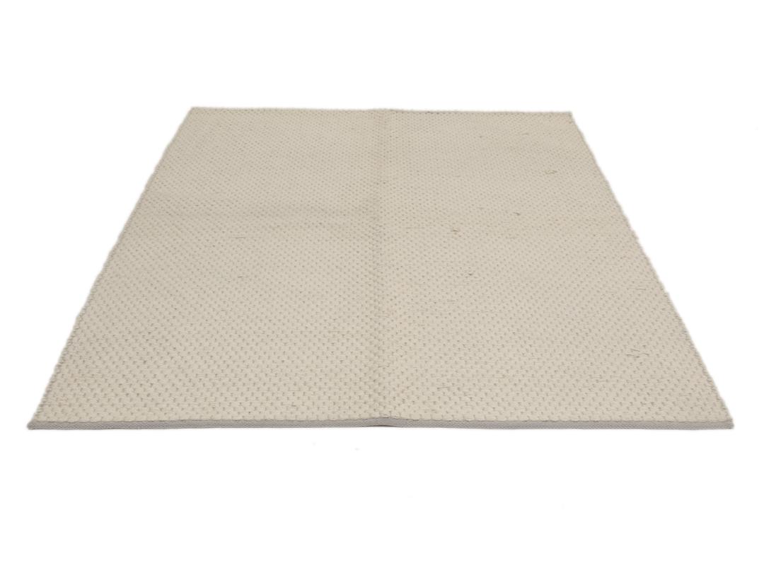 Een minimalistisch handgeweven vloerkleed uit India in een zachte beige tint.