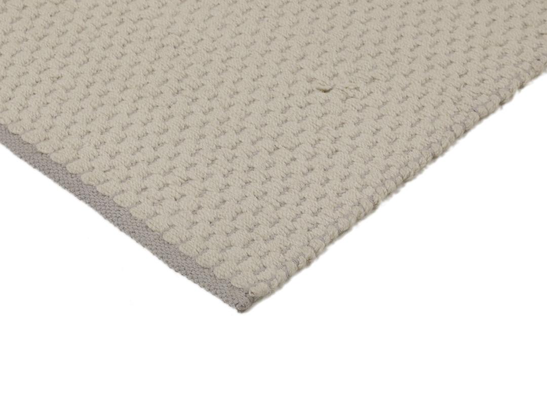Een minimalistisch handgeweven vloerkleed uit India in een zachte beige tint.