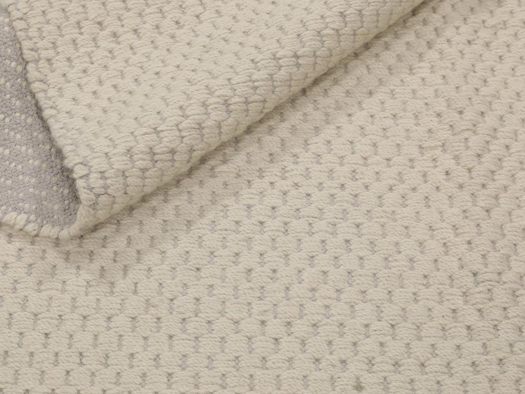 Een minimalistisch handgeweven vloerkleed uit India in een zachte beige tint.