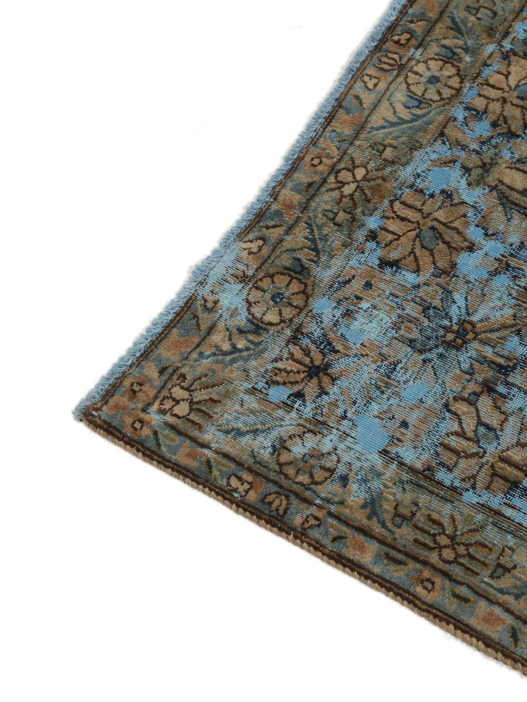 Een groot rechthoekig vintage kleed uit het Midden-Oosten met een bloemendesign in blauwe en bruine tinten.