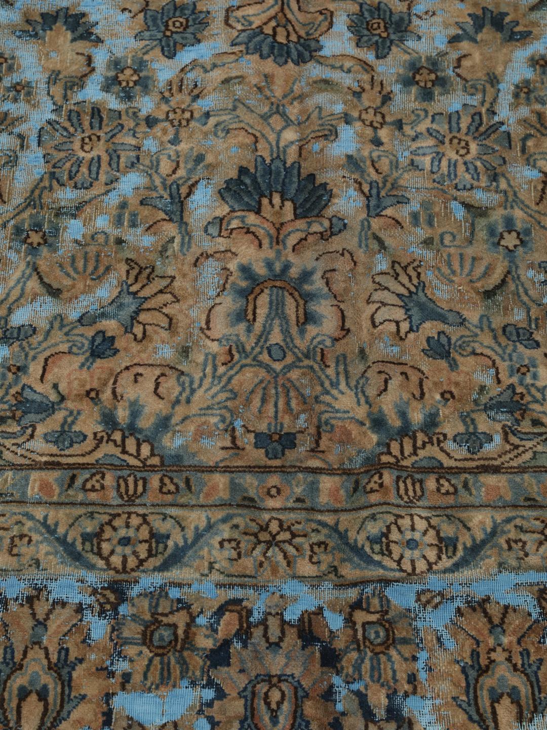 Een groot rechthoekig vintage kleed uit het Midden-Oosten met een bloemendesign in blauwe en bruine tinten.