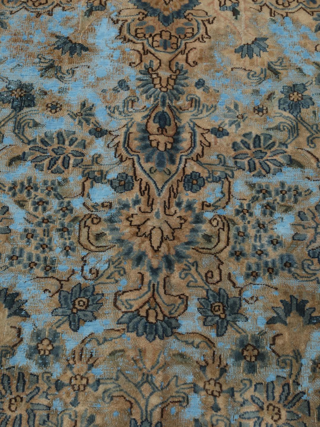 Een groot rechthoekig vintage kleed uit het Midden-Oosten met een bloemendesign in blauwe en bruine tinten.