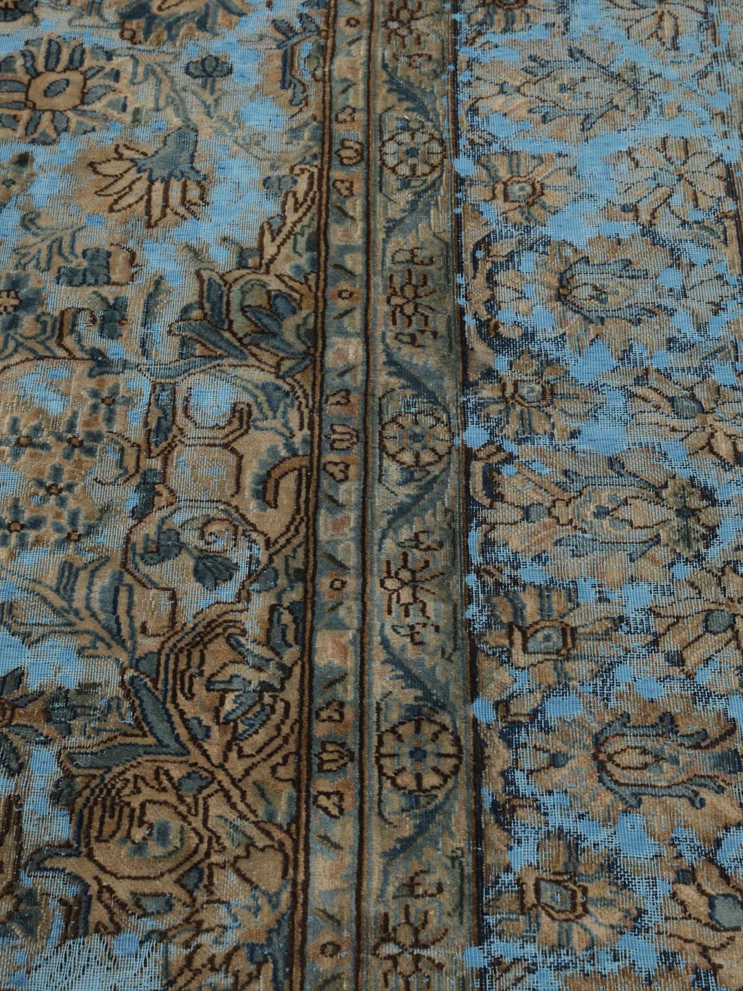 Een groot rechthoekig vintage kleed uit het Midden-Oosten met een bloemendesign in blauwe en bruine tinten.