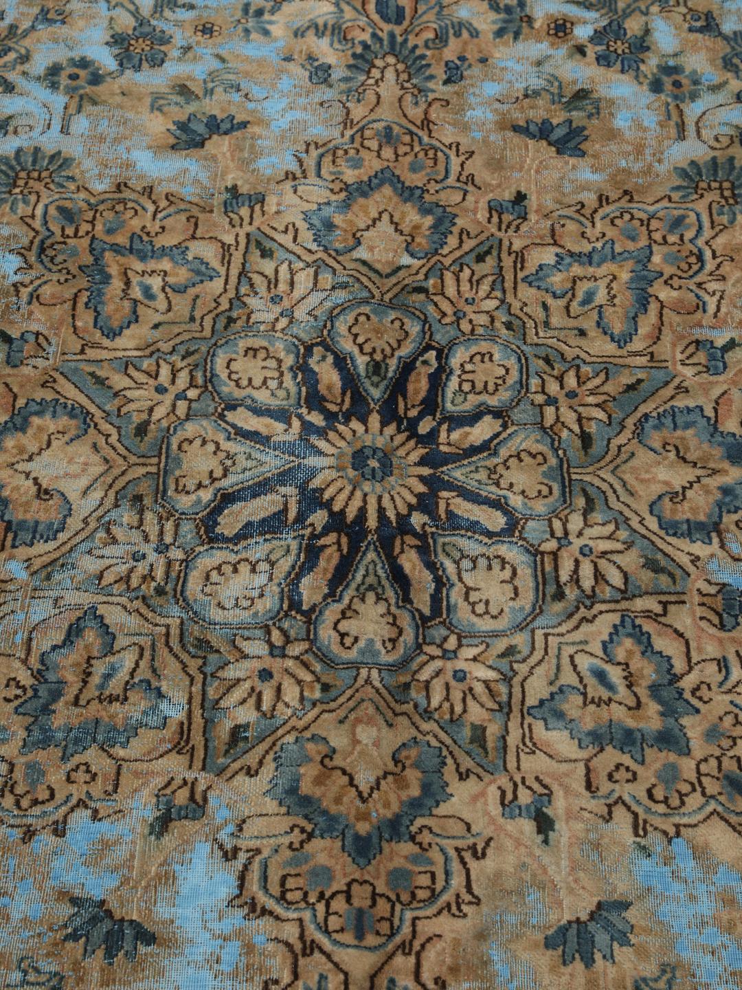 Een groot rechthoekig vintage kleed uit het Midden-Oosten met een bloemendesign in blauwe en bruine tinten.