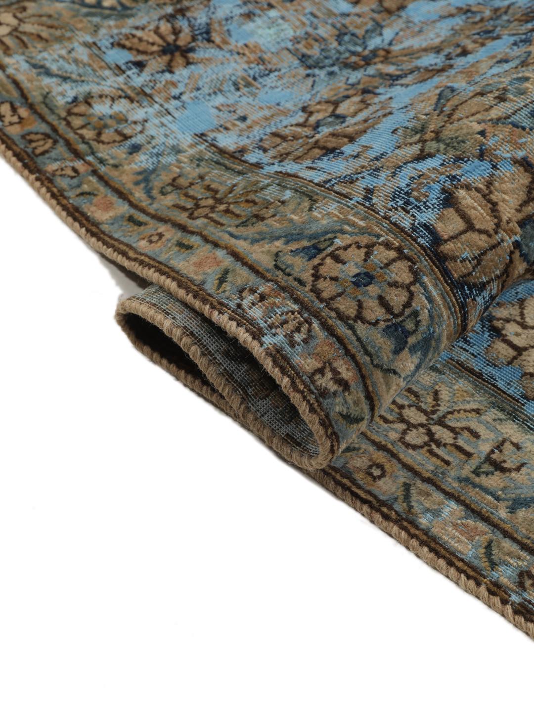 Een groot rechthoekig vintage kleed uit het Midden-Oosten met een bloemendesign in blauwe en bruine tinten.