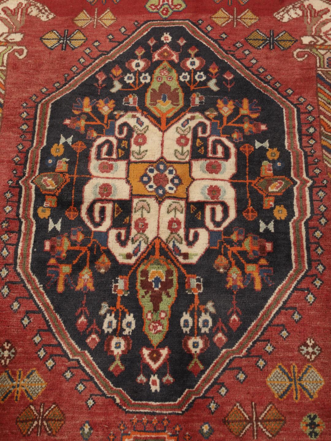 A hand-knotted, one-of-a-kind Qashqai runner rug with a deep red field and intricate geometric medallions.