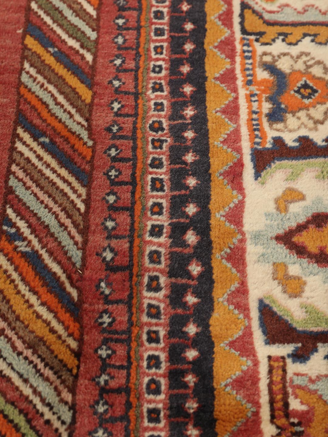 A hand-knotted, one-of-a-kind Qashqai runner rug with a deep red field and intricate geometric medallions.