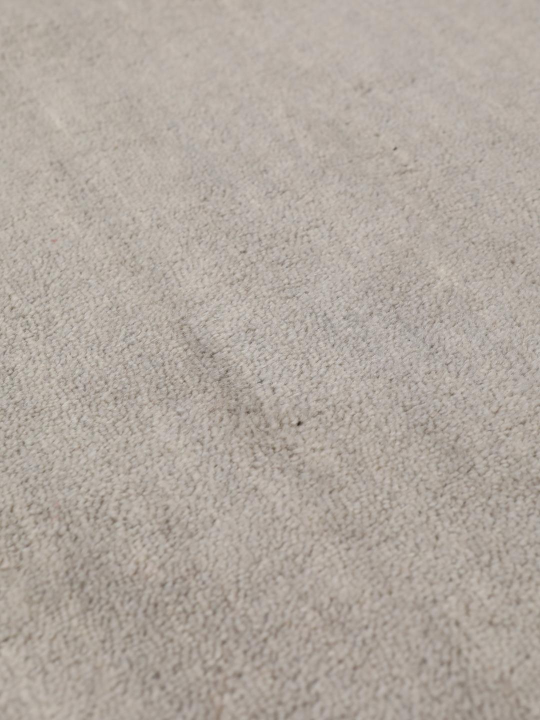Een minimalistisch beige handgeweven tapijt uit India met een zachte, monochrome pool.