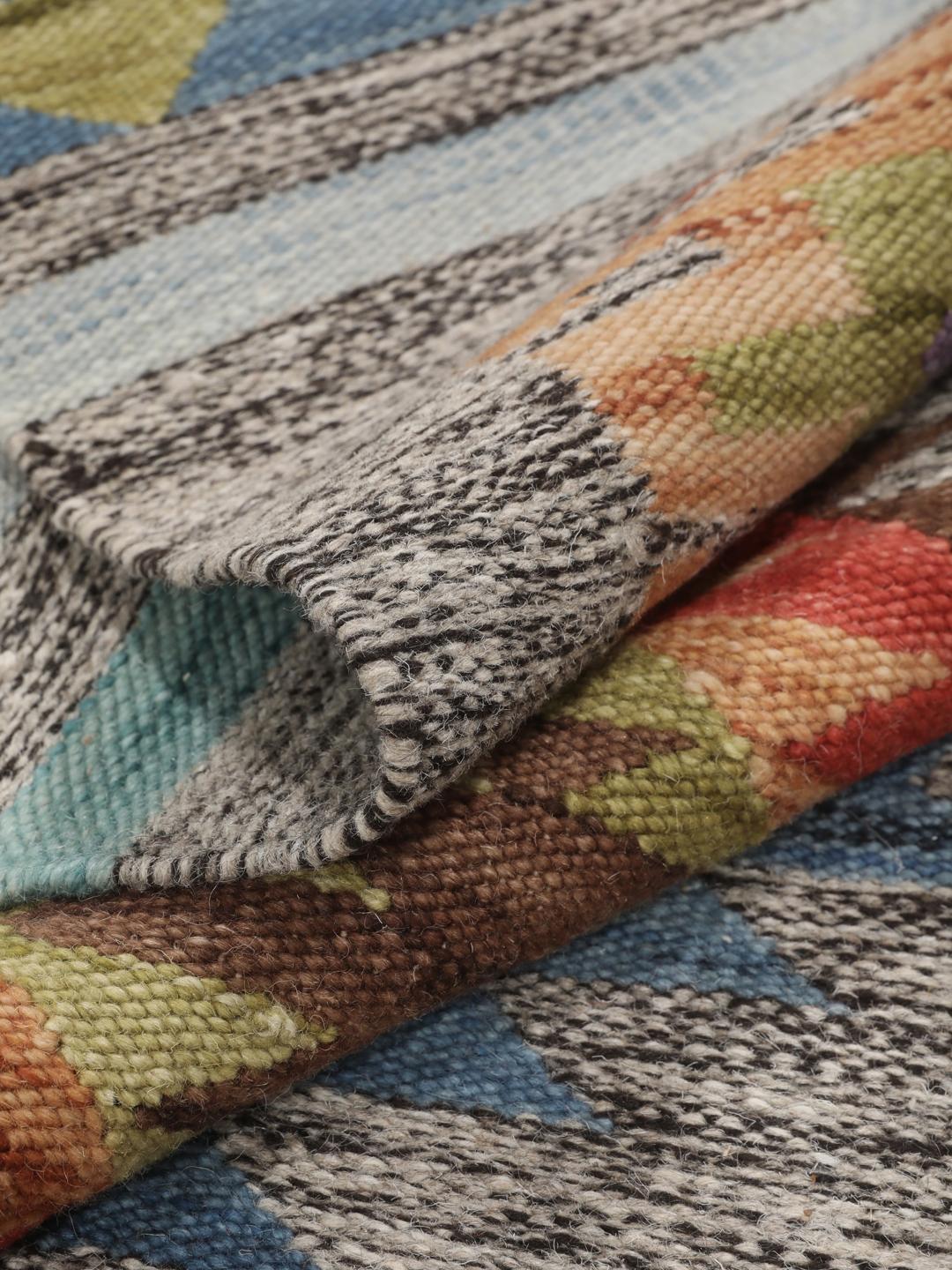 Tapete kilim indiano tecido à mão com padrões de diamante vibrantes sobre um fundo cinzento