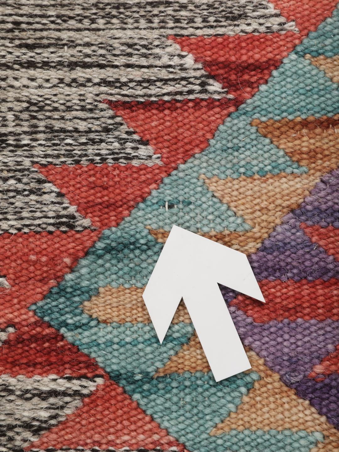 Tapete kilim indiano tecido à mão com padrões de diamante vibrantes sobre um fundo cinzento