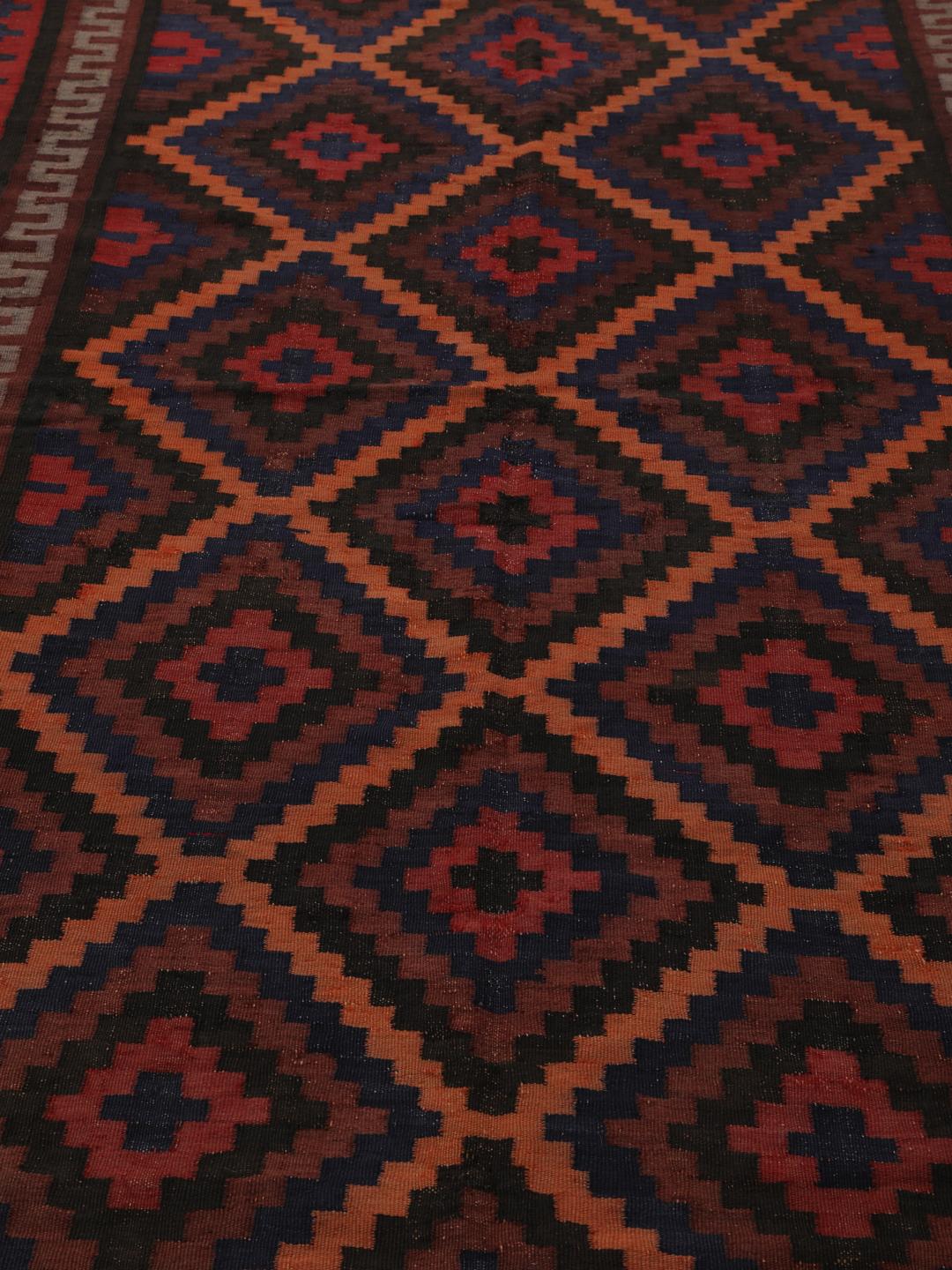 Tapis Kilim vintage afghan avec des motifs géométriques en losange dans des tons rouges et sombres.