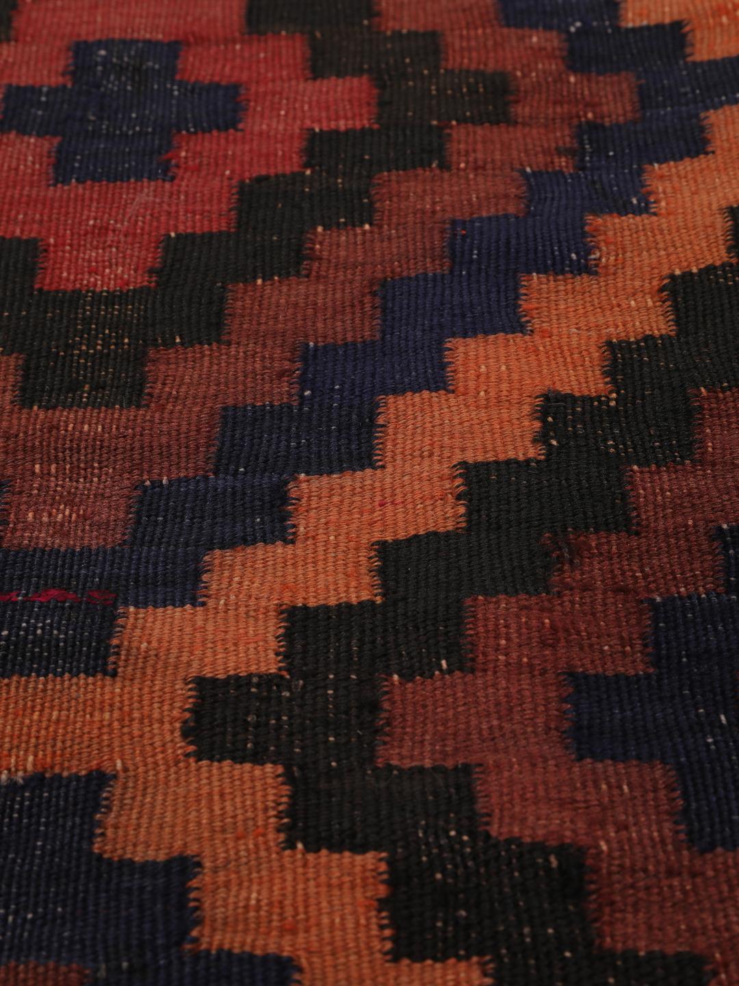 Tapis Kilim vintage afghan avec des motifs géométriques en losange dans des tons rouges et sombres.
