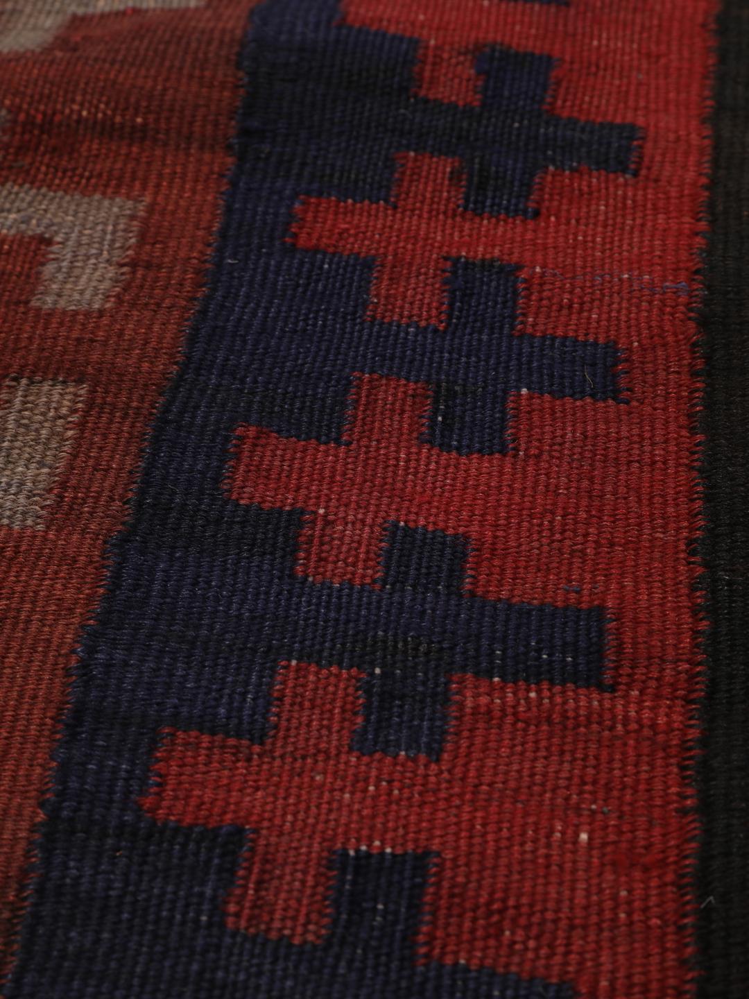 Tapis Kilim vintage afghan avec des motifs géométriques en losange dans des tons rouges et sombres.