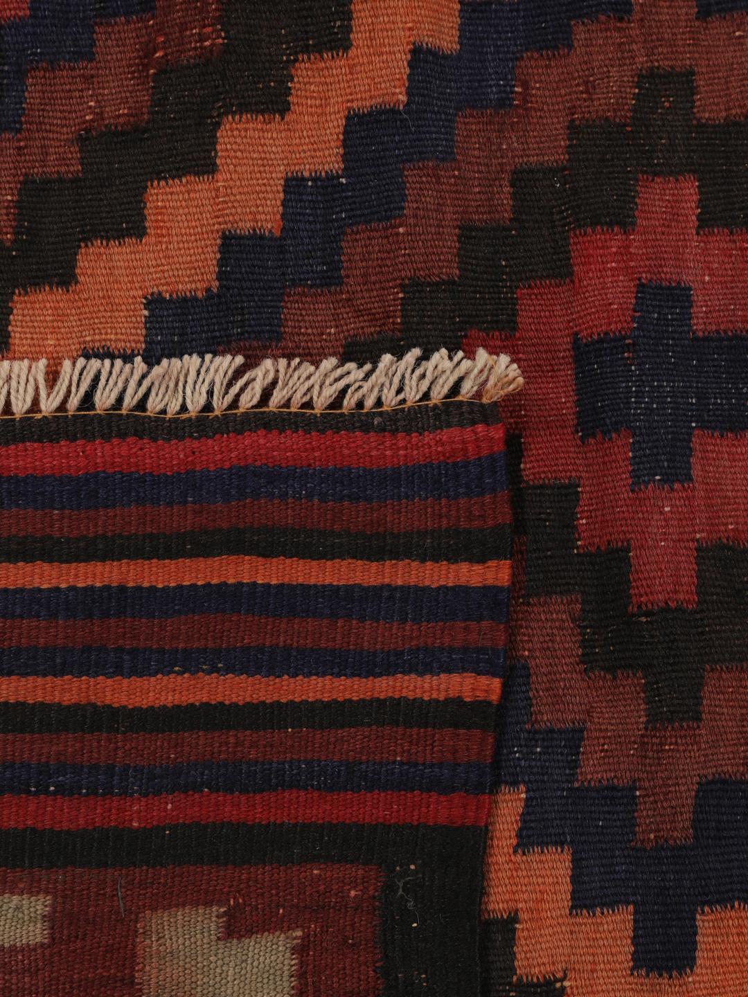 Tapis Kilim vintage afghan avec des motifs géométriques en losange dans des tons rouges et sombres.