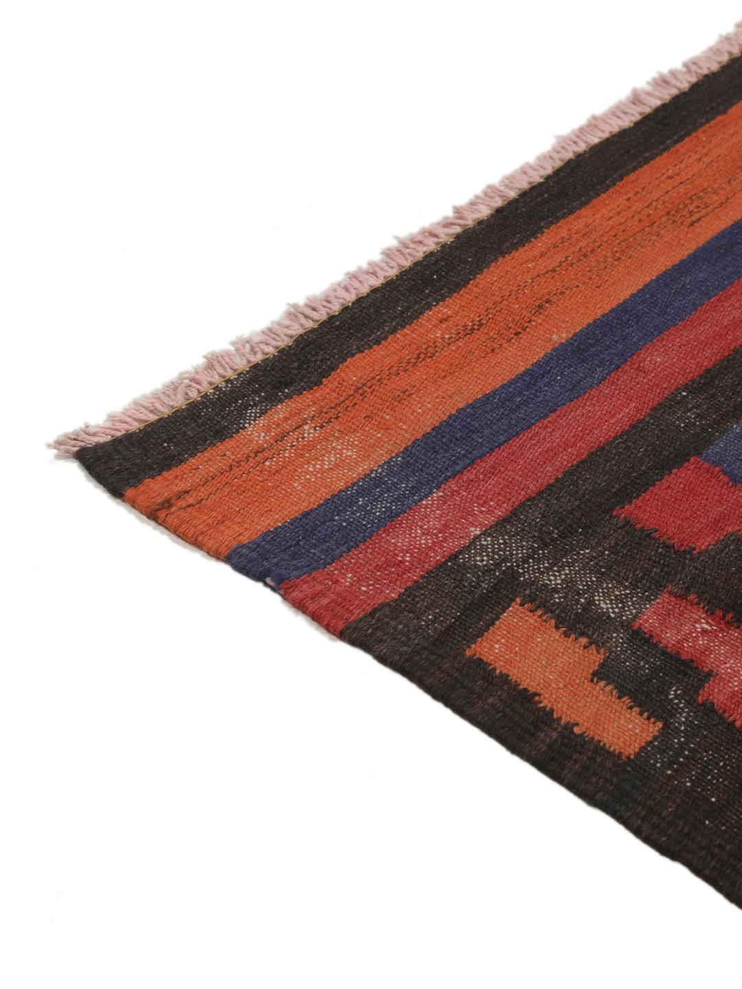 Un long tapis couloir afghan tissé à la main présentant un motif répétitif en losange dans des tons de rouge, bleu et noir.