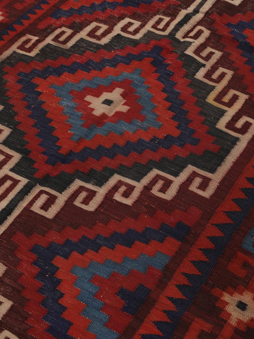 Tapis Kelim afghan tissé à la main avec des motifs géométriques en losange dans les tons rouge, bleu et noir.