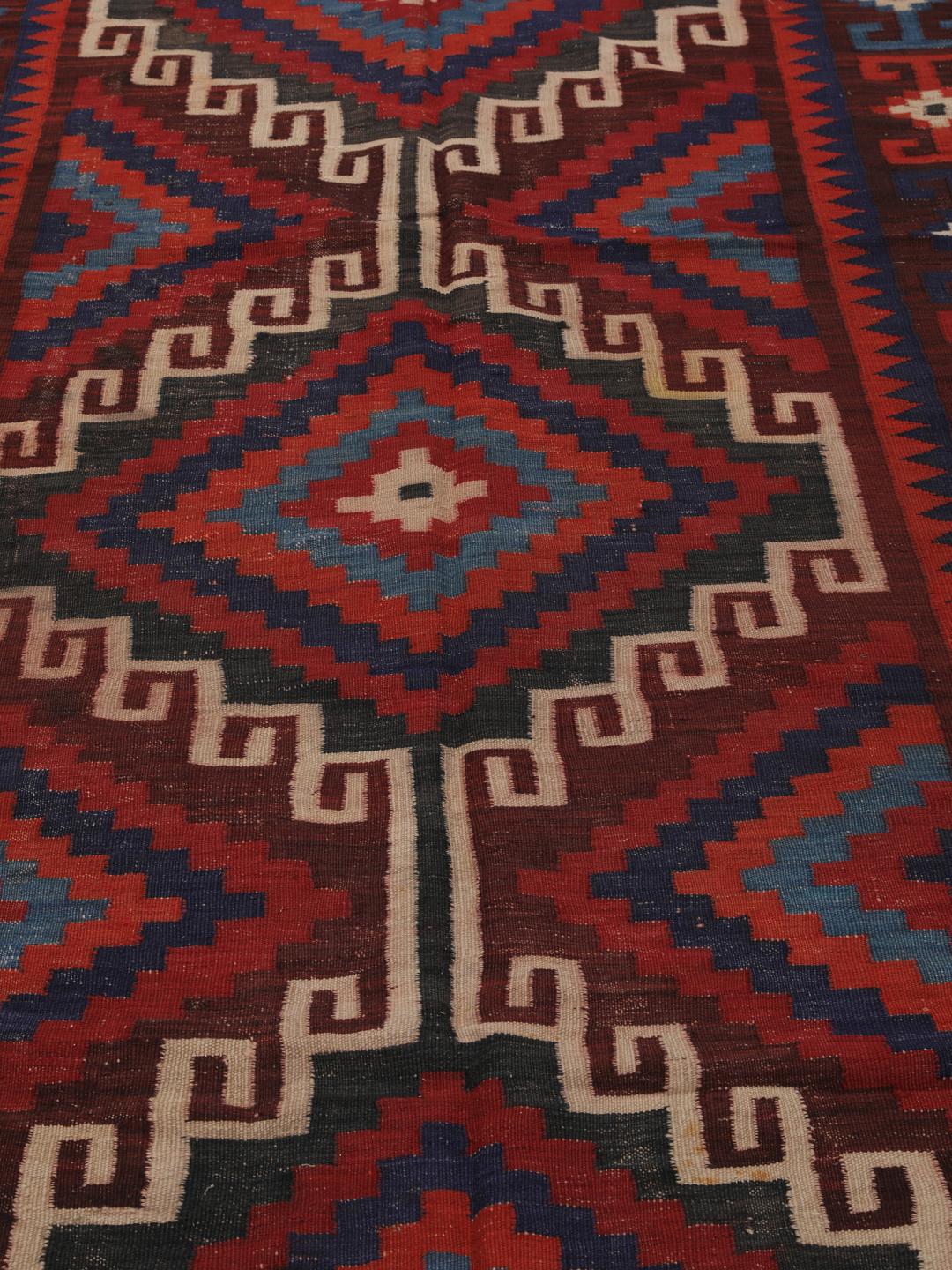 Tapis Kelim afghan tissé à la main avec des motifs géométriques en losange dans les tons rouge, bleu et noir.